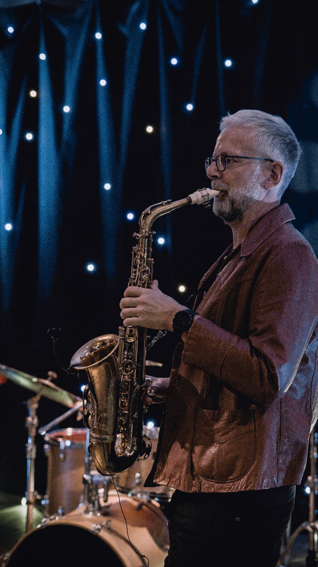 Ulli Jünemann spielt Altsaxophon vor Sternenvorhang auf der Bühne