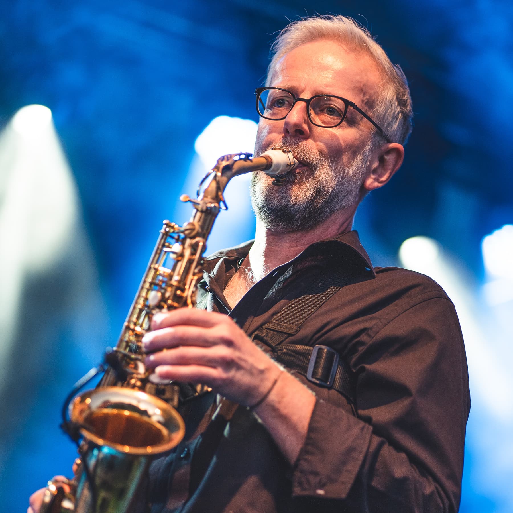 Ulli Jünemann spielt Altsaxophon im blauen Bühnenlicht